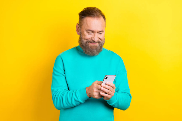 Photo of cheerful attractive man wear stylish clothes us iphone samsung texting sms share repost isolated on yellow color background. - Fotó, kép