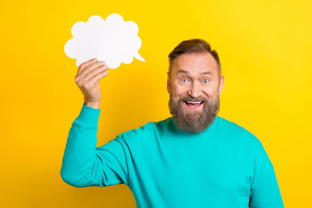 Photo portrait of handsome granddad hold paper comics speech bubble talk wear trendy aquamarine garment isolated on yellow color background. - 写真・画像