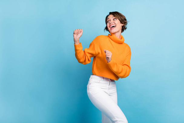 Photo portrait of attractive young woman dancing look empty space party wear trendy orange garment isolated on blue color background. - Foto, imagen