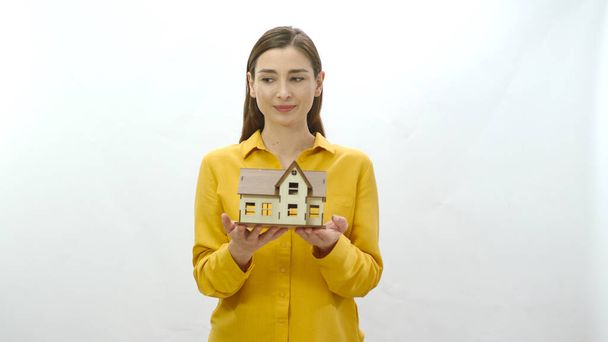 Young woman holding a model of her newly bought or rented house. The woman examines the model of the house and looks at the empty advertising space, drawing attention to the housing crisis. - Photo, image