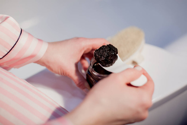 Шпатель с кофейной скраб в руке девушки, для очистки кожи рук - Фото, изображение
