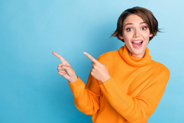 Photo portrait of lovely young lady fingers point empty space excited funky wear trendy orange garment isolated on blue color background. - Fotografie, Obrázek