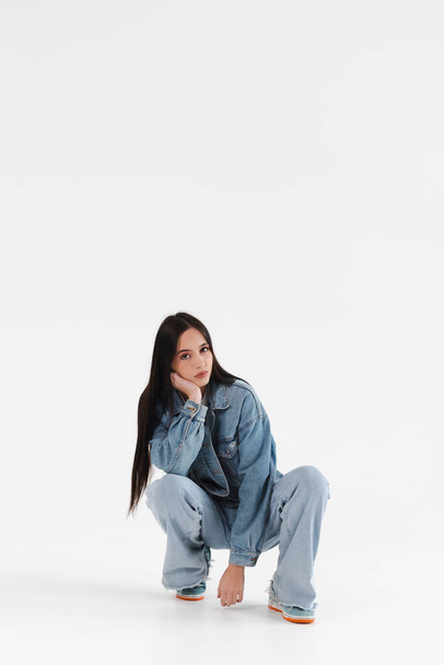 Portrait of a Beautiful Girl dressed in a denim jacket, jeans and sneakers. Isolated on white. - Fotó, kép
