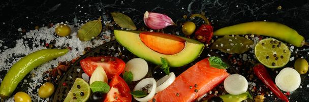 Pink salmon fillet, spices and vegetables on a black background. Wide photo. - Foto, Imagem