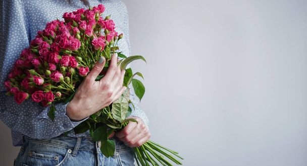 International Women's Day.Concept of greeting banner for international women's day on March 8.Close-up of girl's hands holding gift box and large bouquet of pink roses on gray background,copy space - Fotoğraf, Görsel
