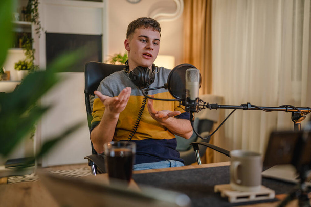 One man caucasian male blogger or vlogger gesticulating while streaming video podcast in broadcasting studio use microphone and headphones famous influencer shooting video for channel podcast - Foto, afbeelding