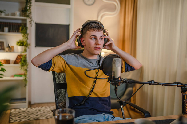 One man caucasian male blogger or vlogger gesticulating while streaming video podcast in broadcasting studio use microphone and headphones famous influencer shooting video for channel podcast - Фото, зображення