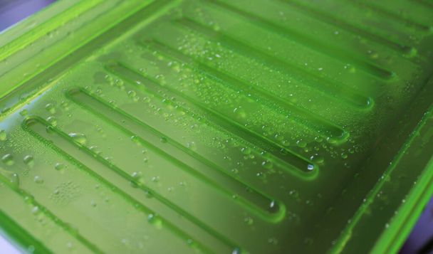 Patrón de gotas de condensación y bombillas de agua en una vista de ángulo de cierre de plástico verde  - Foto, Imagen