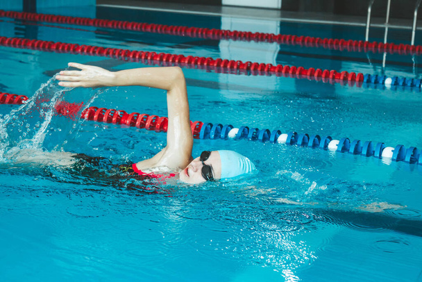 Beautiful female swimmer using front bypass, freestyle in the pool. Preparing professional athletes to win the championship - Fotografie, Obrázek