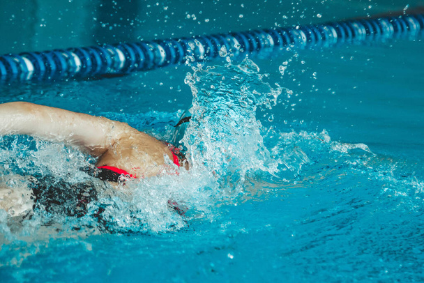 Successful female swimmer swimming in the pool. A professional athlete is determined to win the championship - Foto, Bild
