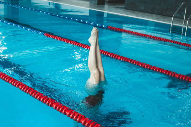 Detail of the legs of a professional woman practicing upside down synchronized swimming in the pool - Foto, Imagen