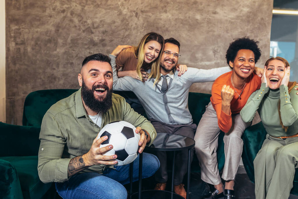 Group of friends watching game in cafe. Friends sitting at a cafe public place screaming and shouting feels overjoyed and happy by their favorite football club team winning - Foto, imagen