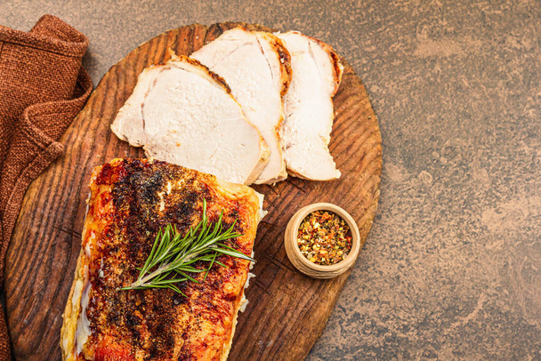 Baked pork loin with spices and herbs on vintage wooden cutting board. Ready to eat meat slices, healthy lifestyle, dinner concept. Brown stone background, flat lay, top view - Photo, Image