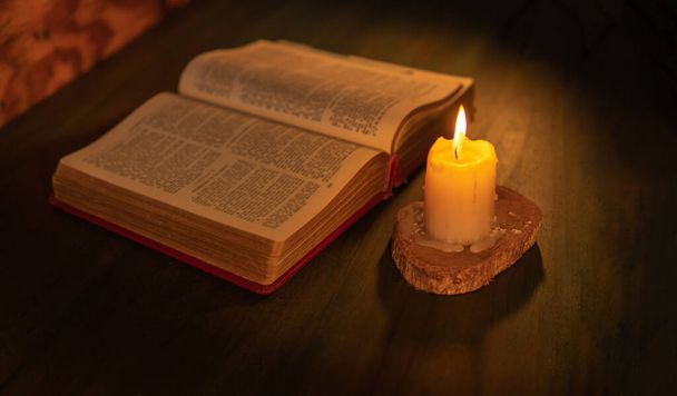 Библия освещена свечами на деревянном столе. религиозного происхождения - Фото, изображение