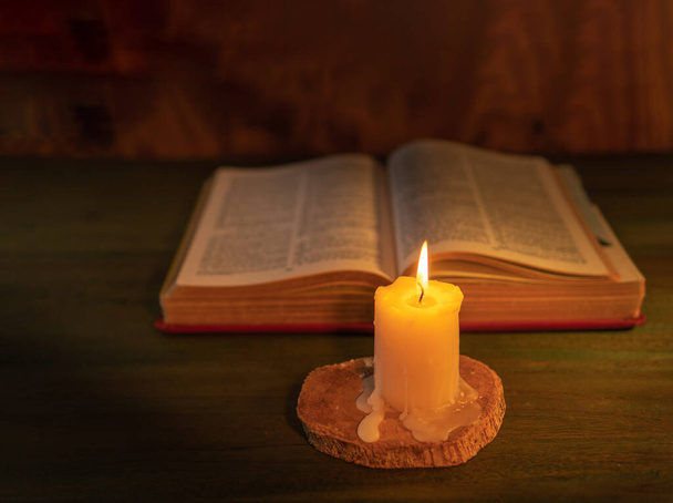 fa hátterű bibliát megvilágító gyertya - Fotó, kép