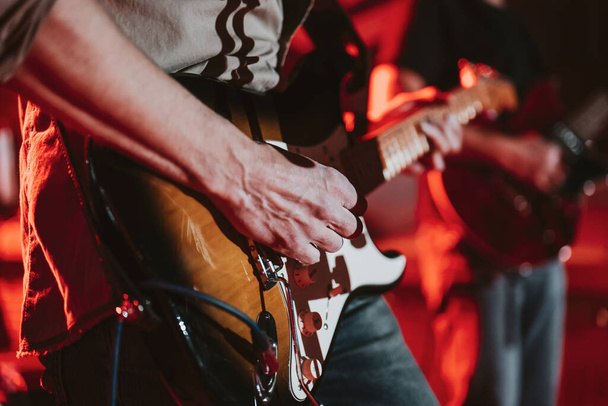 Elektromos gitáron játszó férfi koncert közben, arcok nélkül, sekély mélységélességgel. - Fotó, kép