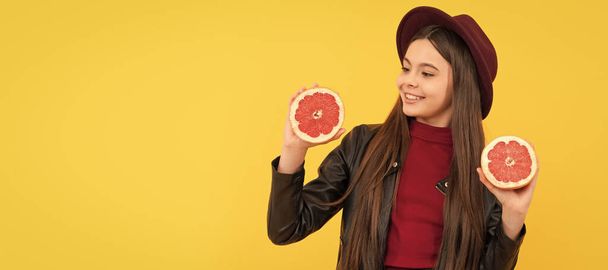 gelukkig tiener meisje in hoed en lederen jas houden gesneden grapefruit. Kinderportret met pompelmoes oranje, horizontale poster. Banner header met kopieerruimte - Foto, afbeelding