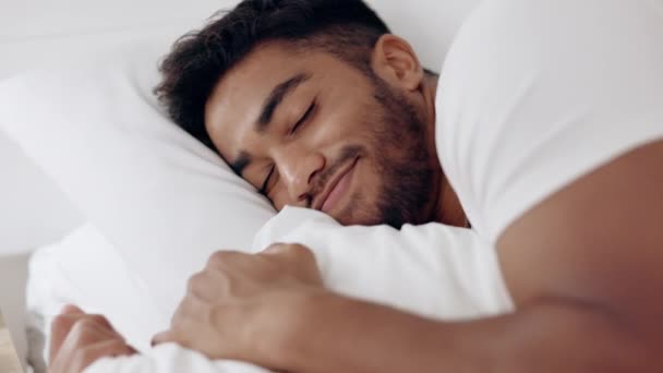 Face of happy man sleeping in bed, morning and at home for relaxing wellness, comfortable pillow and healthy rest. Young guy asleep in bedroom with smile, happiness and peaceful dreams on mattress. - Footage, Video