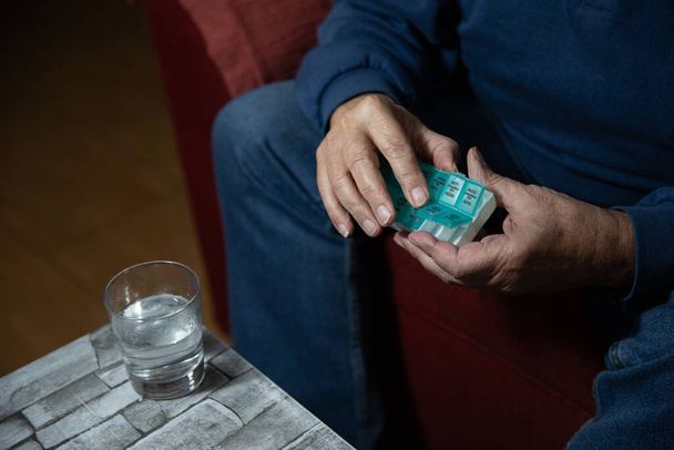 Close up of an elderly gentleman's hands taking pills from his pill organizer. - Fotografie, Obrázek