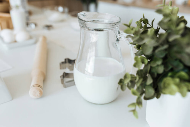 milk in a glass jug on the kitchen table - Foto, afbeelding