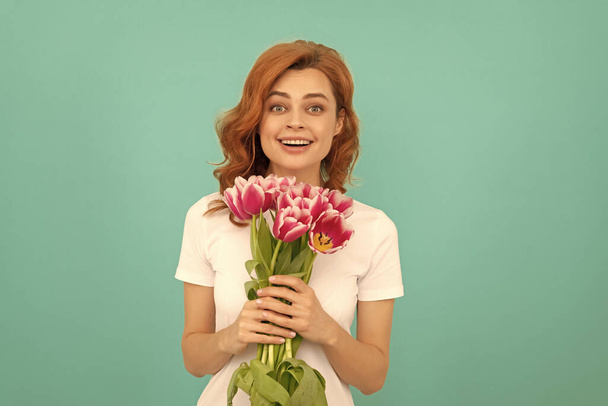 изумленная девушка с цветочным букетом тюльпана на синем фоне. - Фото, изображение