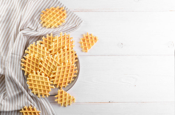Ferratelle or pizzelle a traditional dessert or cookies on a plate on a white wooden background, copy space, top view. Regional cuisine of Abruzzo, Italy. Like the well-known waffle - Fotografie, Obrázek