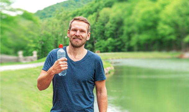 Sportowiec w parku z butelką czystej wody - Zdjęcie, obraz