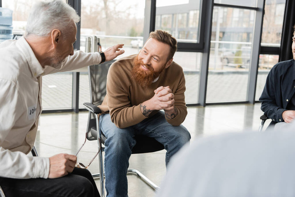 Mature man comforting smiling person with alcohol addiction in rehab center  - Photo, Image