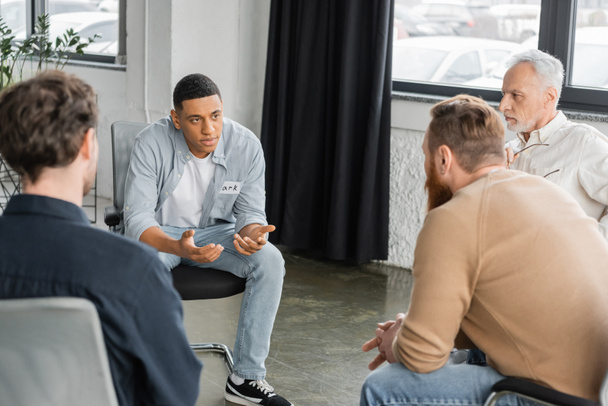 Homme afro-américain avec problème de partage de dépendance à l'alcool lors d'une séance de thérapie de groupe dans un centre de réadaptation  - Photo, image