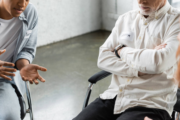 Cropped view of african american person talking to man during alcoholics meeting in rehab center  - Fotografie, Obrázek