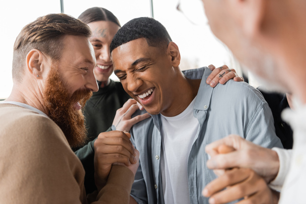 Pozitivní lidé objímají afrického amerického muže během setkání alkoholiků a terapie v rehabilitačním centru  - Fotografie, Obrázek