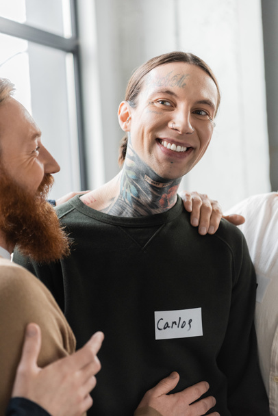 Ihmiset halaavat hymyilevä tatuoitu mies aikana alkoholistien kokouksessa kuntoutuskeskuksessa  - Valokuva, kuva