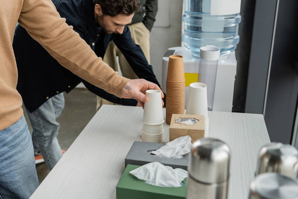 Man with alcohol addiction taking paper cup in rehab center  - Photo, Image