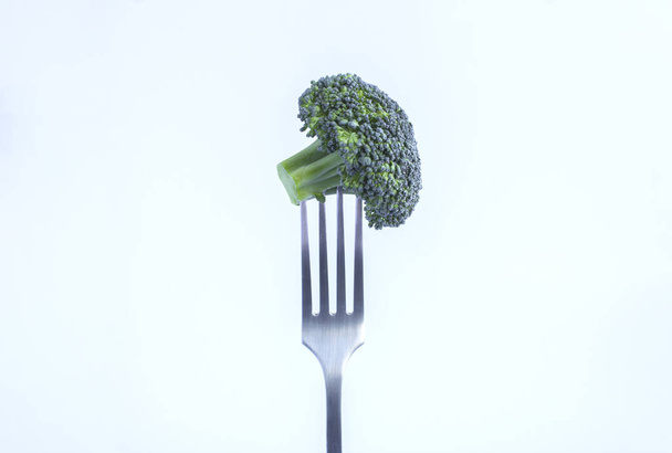 Broccoli stabbed on a silver fork on the white background. Close-up. Copy space. - Photo, Image
