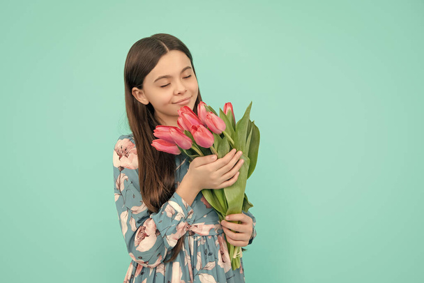 Blumengeschenk. fröhliches Kind riecht Tulpen. Mutter- oder Frauentag. Kinder halten Blumen für den 8. März in der Hand. Teenager-Mädchen mit Frühlingsstrauß auf blauem Hintergrund. - Foto, Bild