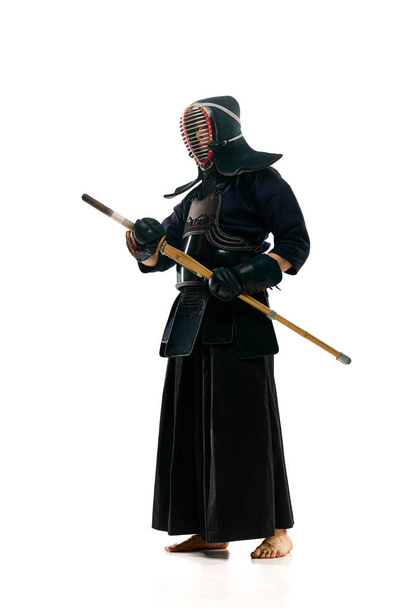 Porträt eines Mannes, professioneller Kendo-Athlet in Uniform, der mit einem Shinai-Schwert vor weißem Studiohintergrund posiert. Konzept aus Kampfkunst, Sport, japanischer Kultur, Action und Bewegung - Foto, Bild