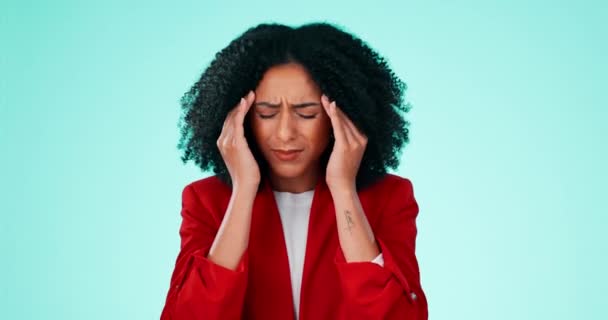 Stress, headache and anxiety with a black woman rubbing her head in pain in studio on a blue background. Mental health, burnout and migraine with an attractive young female messaging her temples. - Felvétel, videó