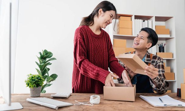 Young asian people couple Male and female small business owner checking online orders and packing the product together - Foto, imagen