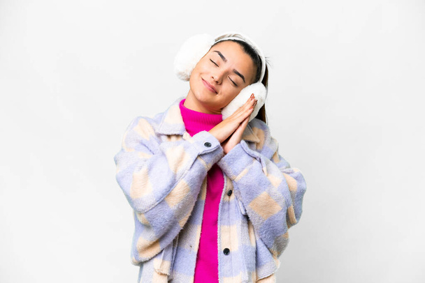 Jeune femme portant des manchons d'hiver sur fond blanc isolé faisant geste de sommeil dans une expression dorable - Photo, image
