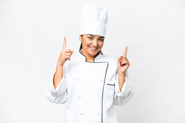 Mujer joven Chef sobre fondo blanco aislado señalando una gran idea - Foto, Imagen
