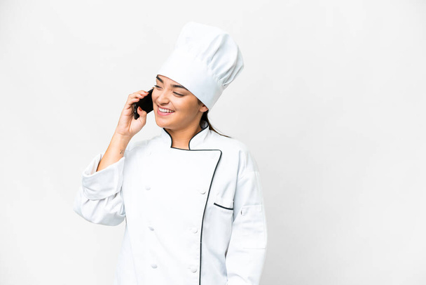 Молодая женщина Шеф-повар на изолированном белом фоне ведет разговор с кем-то - Фото, изображение