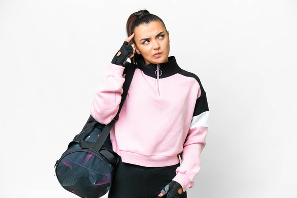 Young sport woman with sport bag over isolated white background having doubts and with confuse face expression - Fotografie, Obrázek