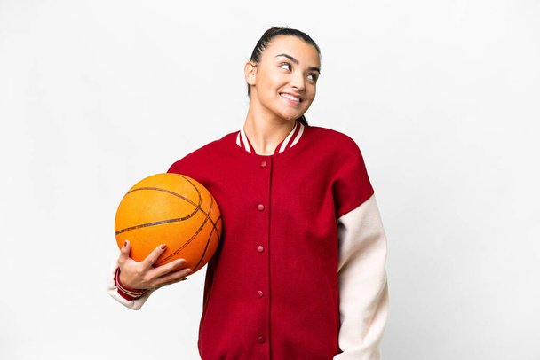 jonge vrouw spelen basketbal over geïsoleerde witte achtergrond denken een idee terwijl op zoek omhoog - Foto, afbeelding