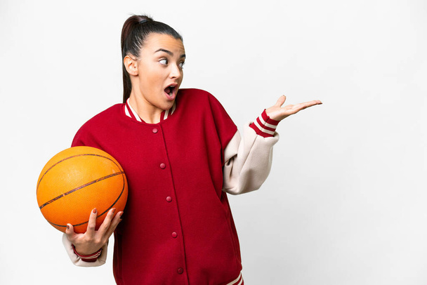 Young Woman playing basketball over isolated white background with surprise expression while looking side - Φωτογραφία, εικόνα