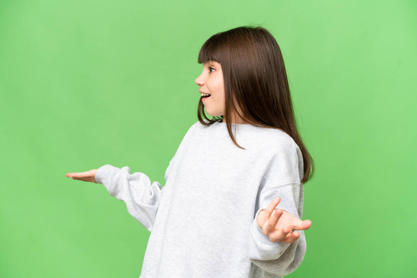 Маленька дівчинка над ізольованим зеленим хромосом ключовим фоном з несподіваним виразом, дивлячись збоку
 - Фото, зображення