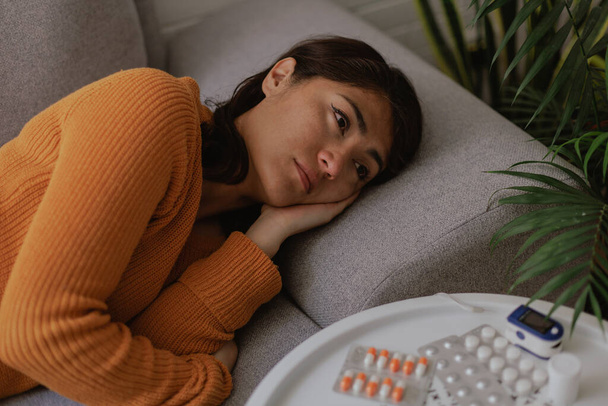 Latin woman lying on the sofa sick. Physical discomfort and depression. Illness and treatment concept. - Valokuva, kuva