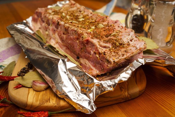 Vers varkensvlees ribben, vlees gemarineerd en voorbereid gebraad met knoflook in een folie - Foto, afbeelding
