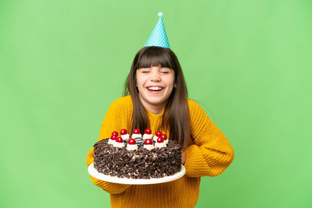 Küçük kız, izole edilmiş krom arka planda doğum günü pastasını tutarken gülümsüyor. - Fotoğraf, Görsel