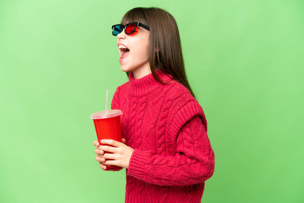 Menina segurando refrigerante sobre fundo chave croma isolado rindo em posição lateral - Foto, Imagem