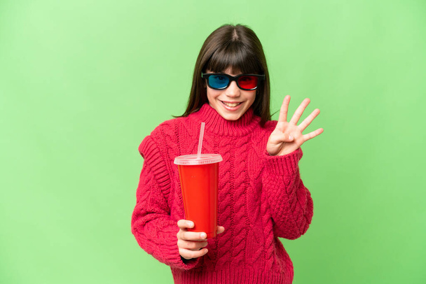 Kleines Mädchen hält Soda über isoliertem Chroma-Schlüsselhintergrund glücklich und zählt mit den Fingern vier - Foto, Bild
